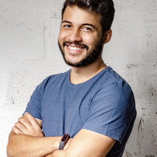 Portrait of John, a man standing against a grey background.